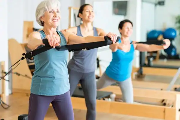 Toning Arms After 60: Empowering Womens Fitness Through Effective Weight Training 2 older woman doing weight training Doancaster and resistance in the gym to tone upper arms